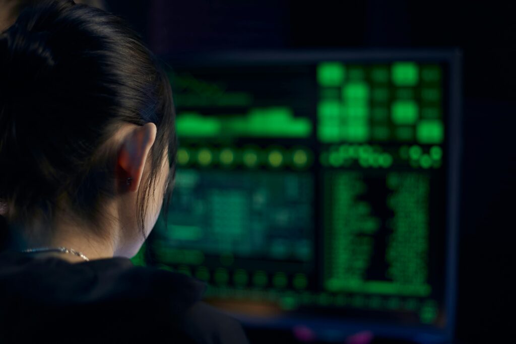 A woman focuses on data displayed on a computer screen in a dark room.